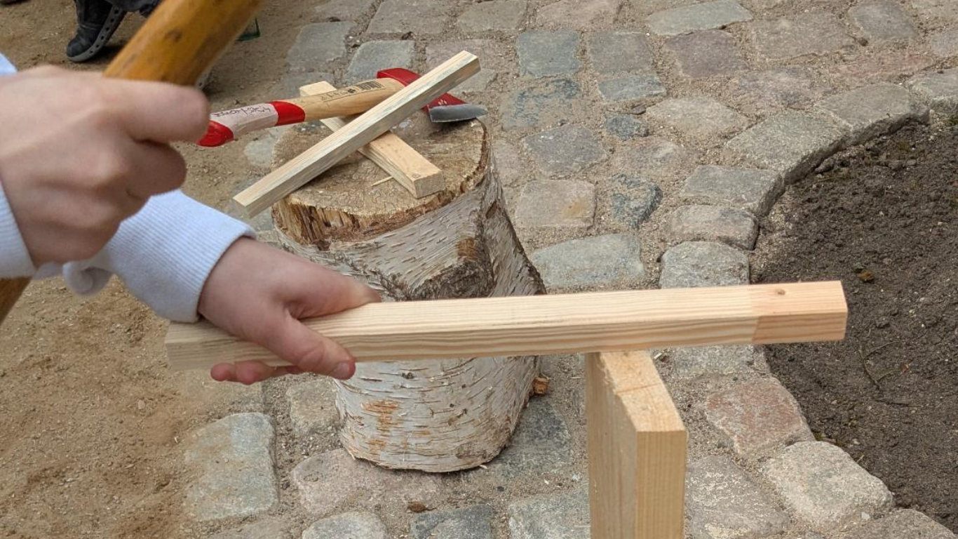 Unter Anleitung spalten die Kinder der Max-Brauer-Schule das Holz für ihr Feuer im Heilgarten Hamburg